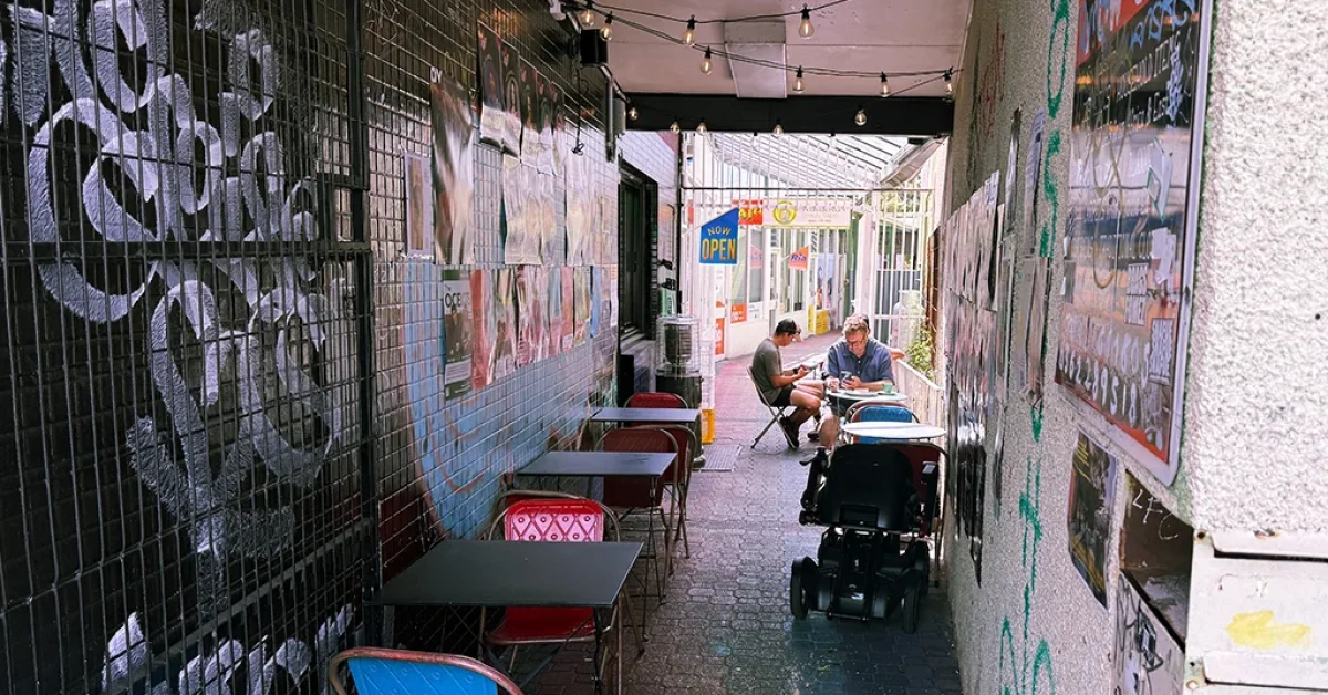 An alley in Moonah with cafe seating, festoon lighting, gig posters and graffiti. Patrons sit and enjoy a coffee.